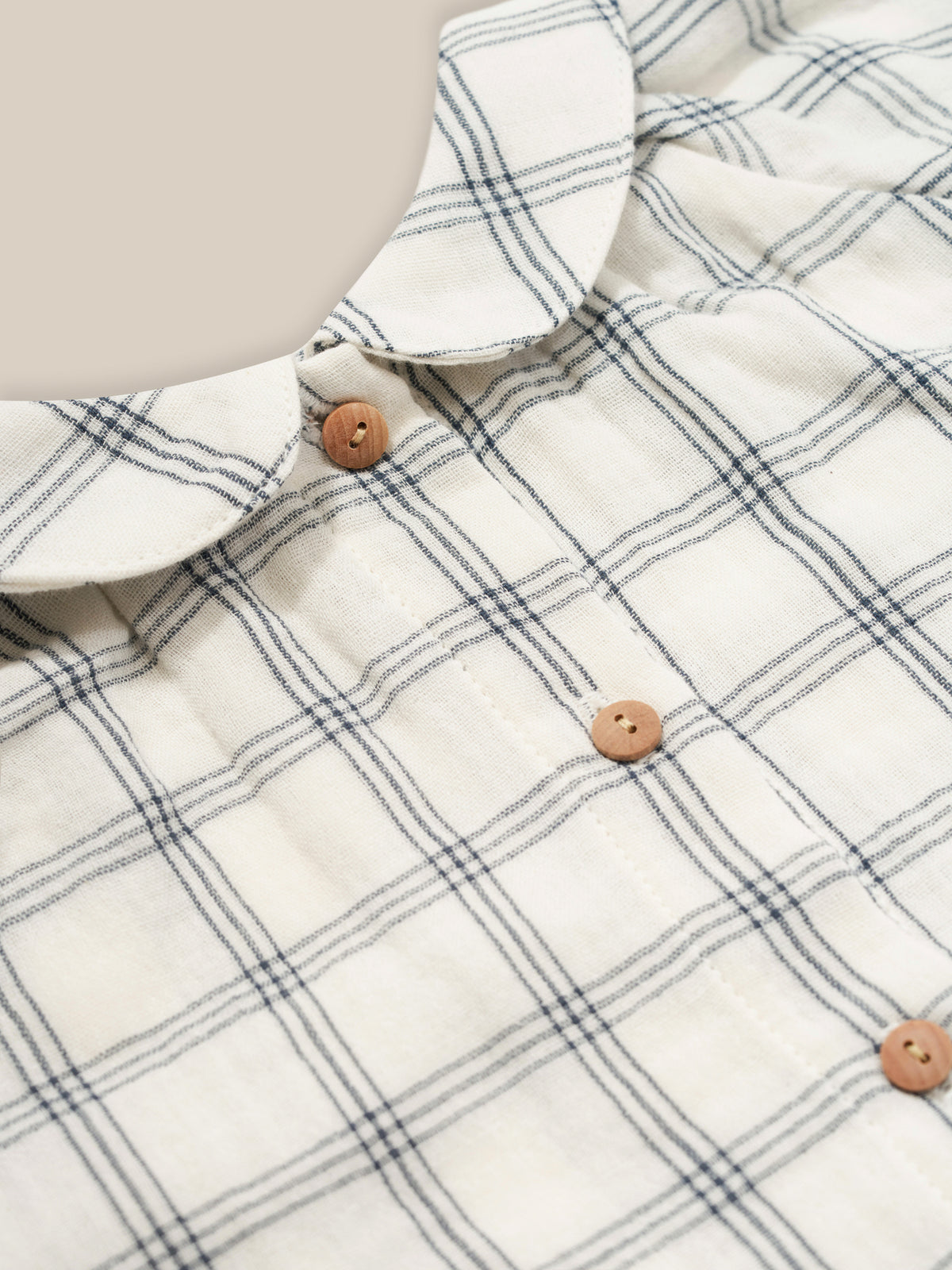 close up of baby navy window check long sleeved two-way muslin button-down white dress with peter pan collar