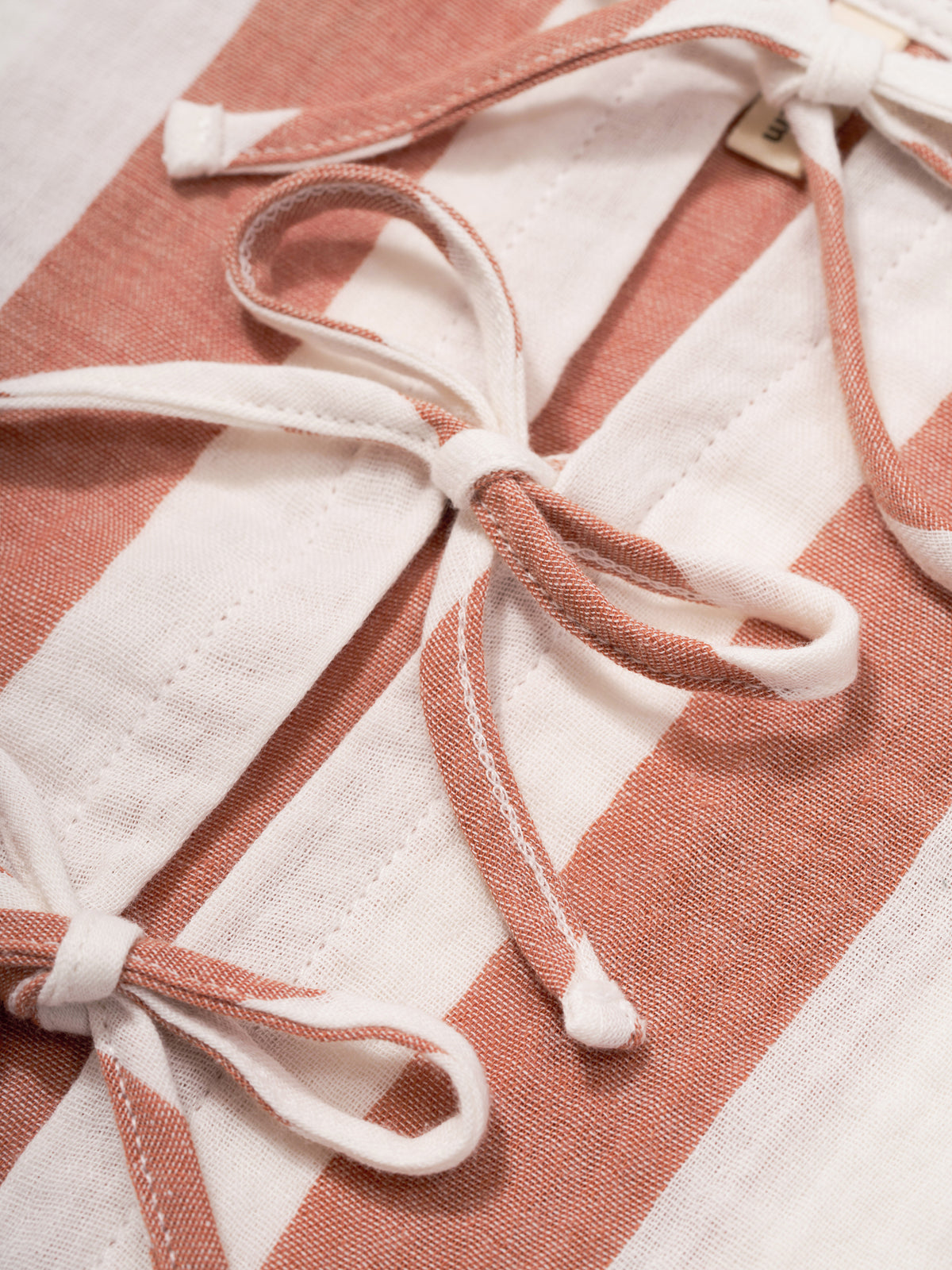 close up of toddler two-way ribbon-tie sleeveless organic muslin top in red & white stripes