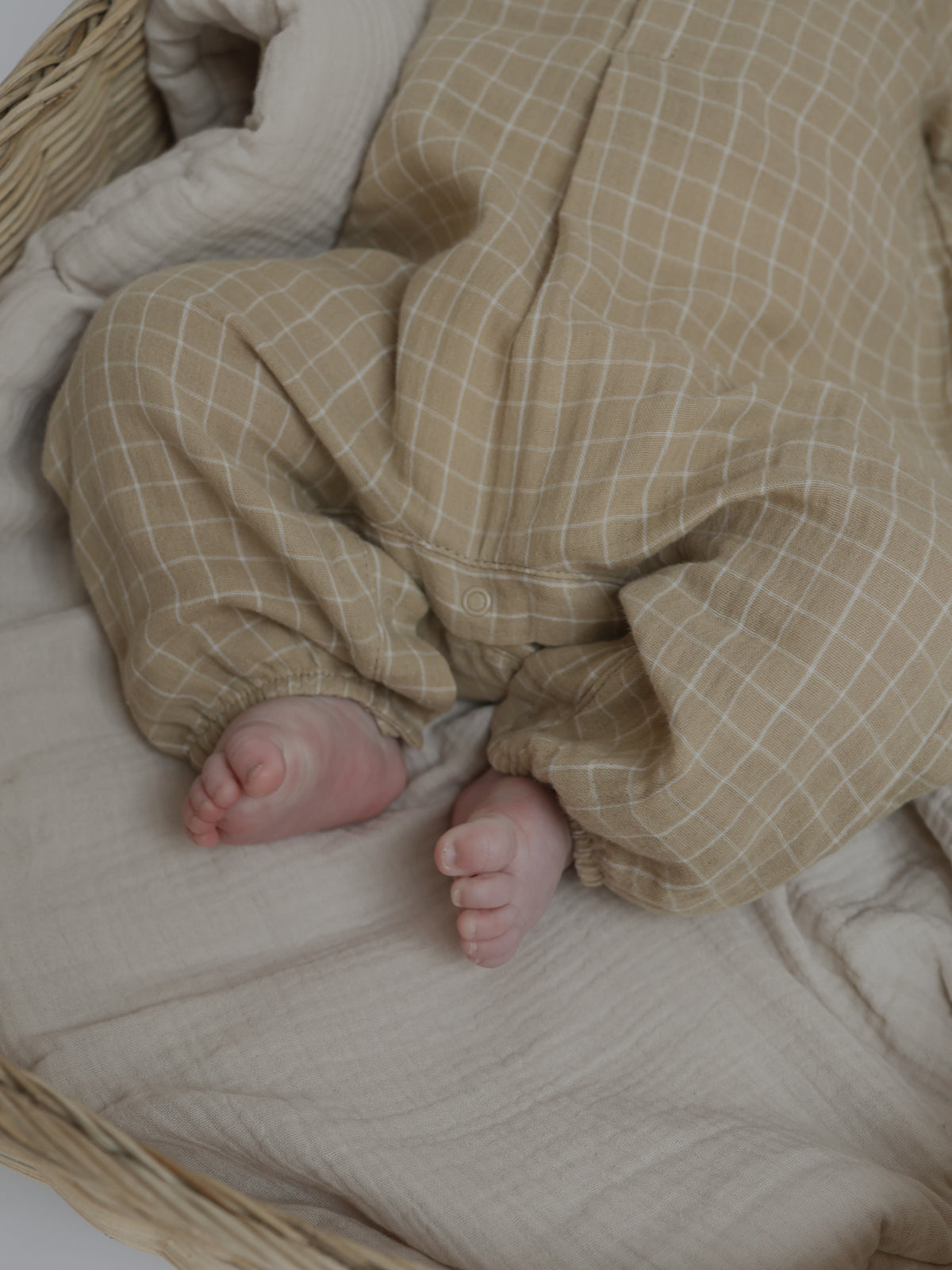 baby in soft breathable organic muslin onesie with timeless grid pattern & elastic cuffs