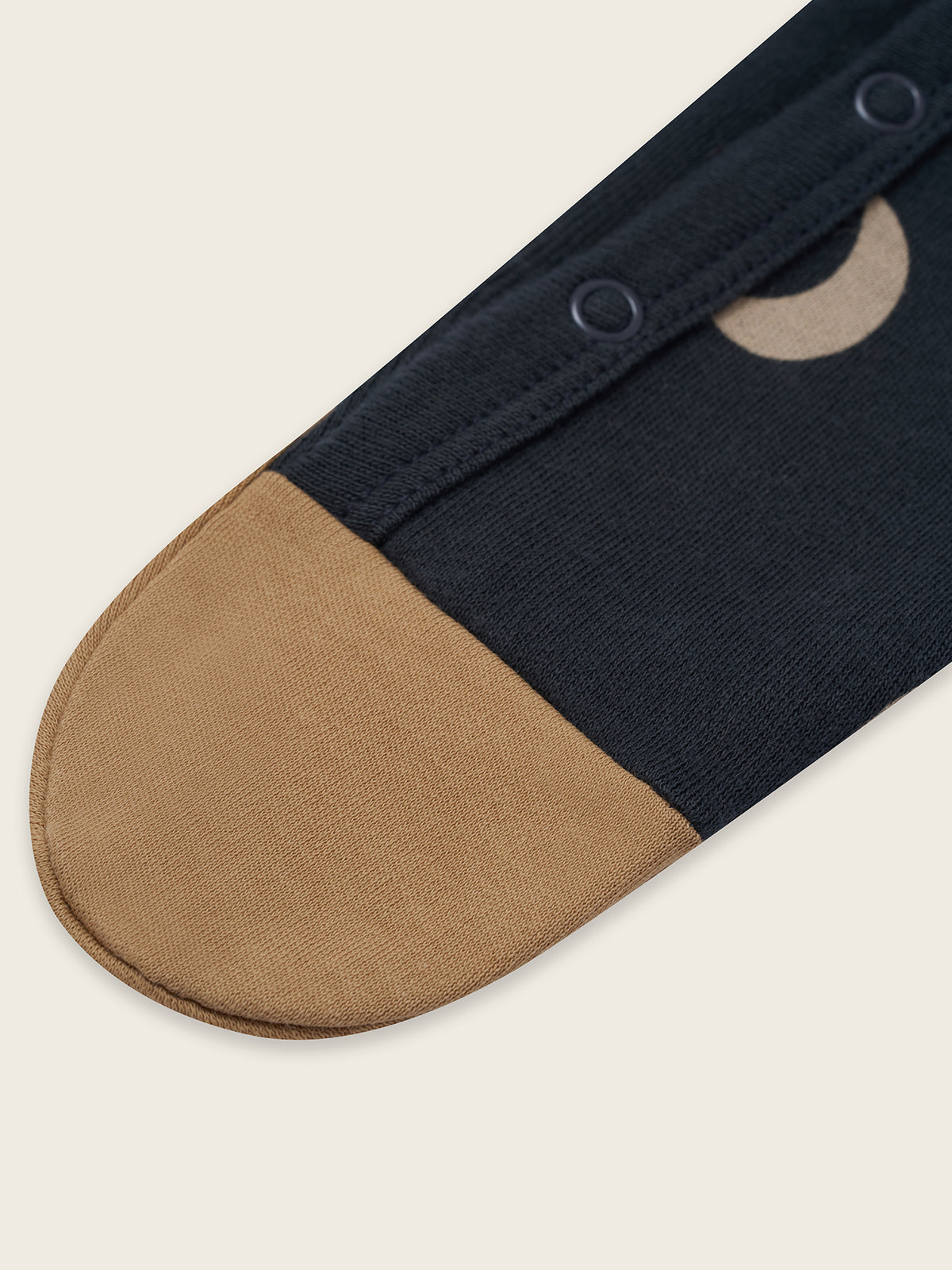Navy and beige onesie detail on a light beige background