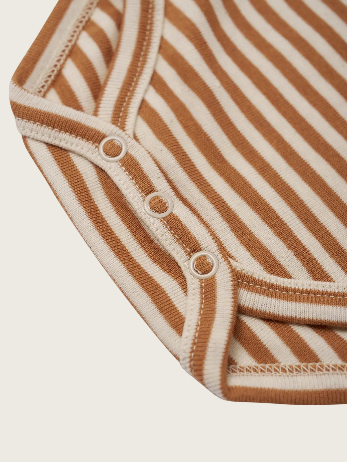Close-up of a brown and beige striped baby onesie on a white background