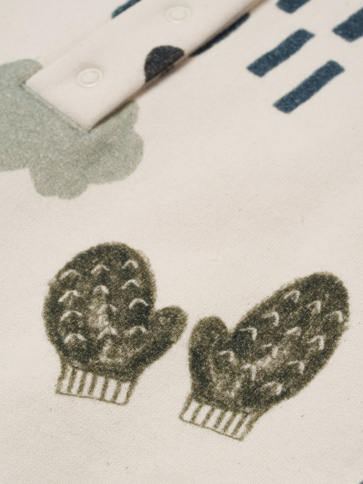 close up of cream undyed cotton onesie with cosy nature-themed hand-drawn illustrations