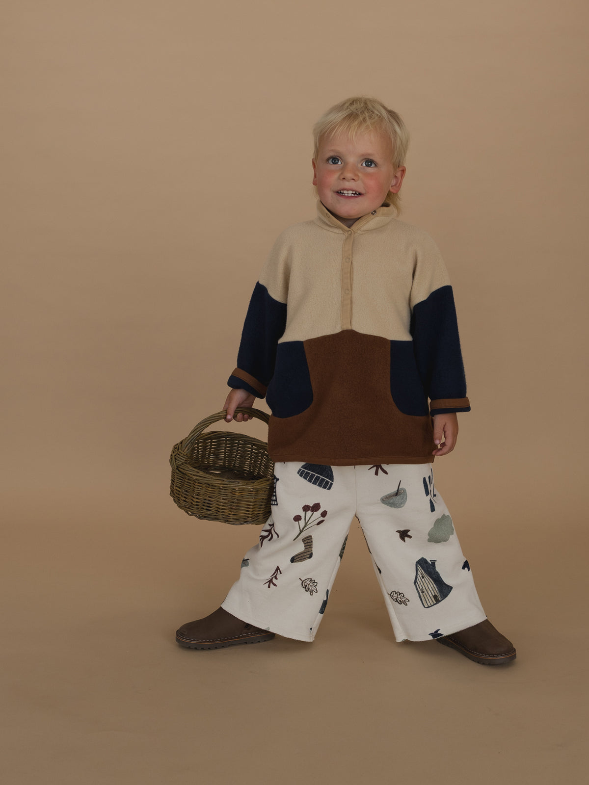 toddler in wide leg pants with cosy nature-themed print & colour block sweater, standing legs apart