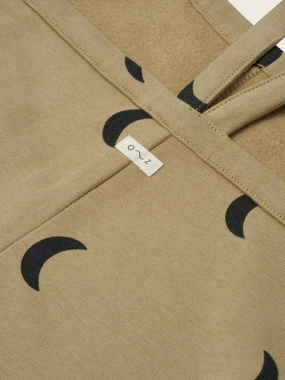 close up of toddler dusky beige oversized boxy terry cotton dungarees with black crescent moon print