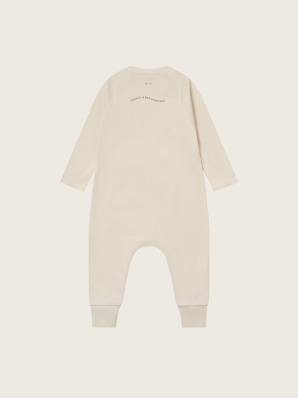 baby cream undyed cotton playsuit with organic & raw since 2010 slogan, and ribbed ankle cuffs