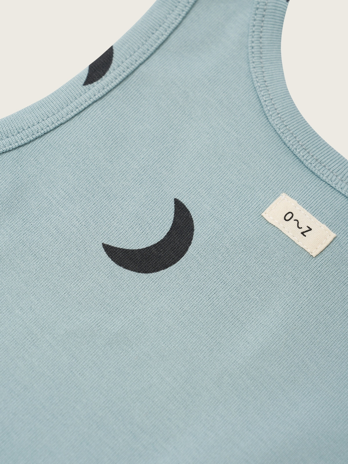 Light blue sleeveless shirt with black crescent moon design and size label on a white background