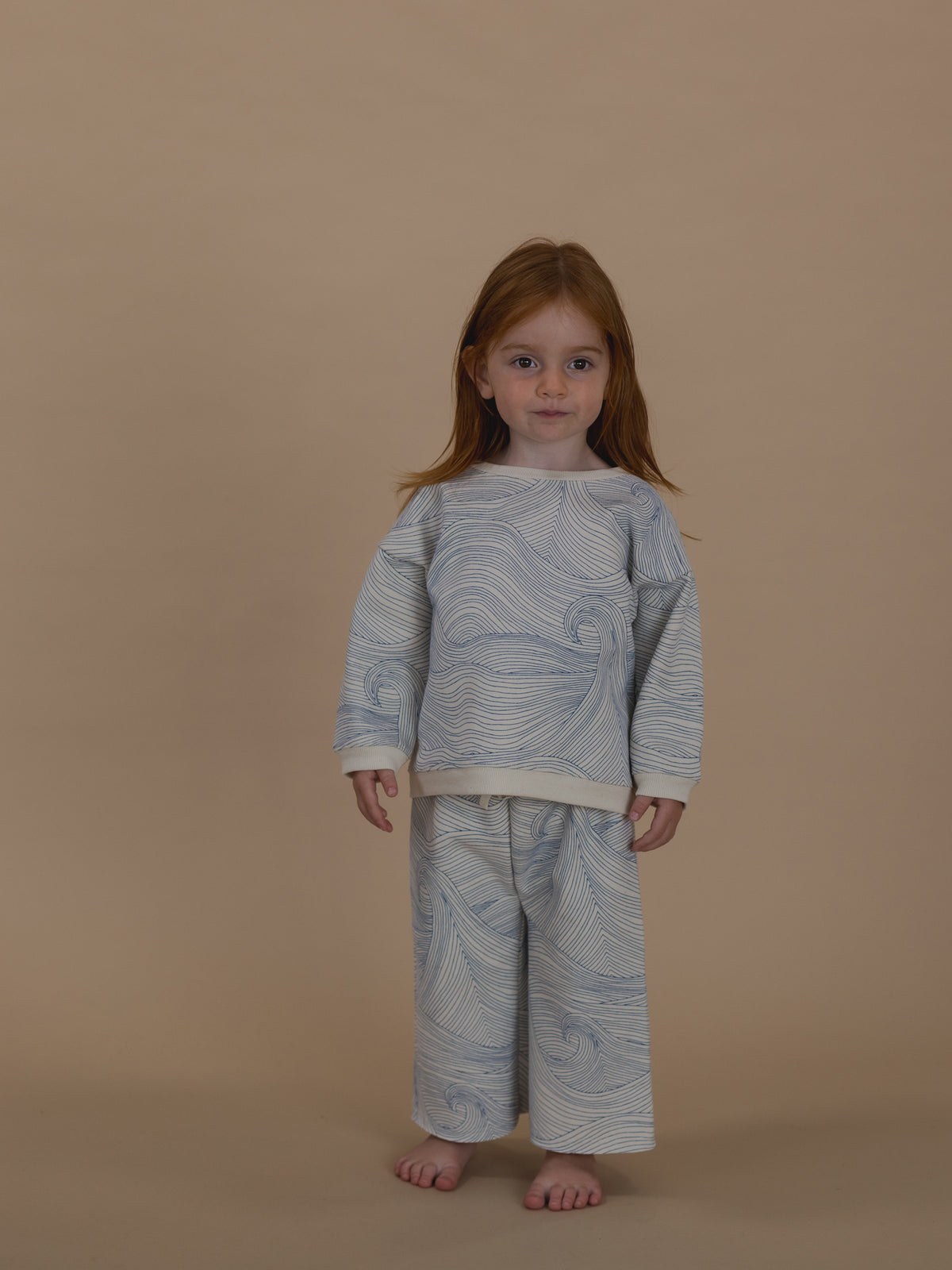 toddler in cream cotton sweatshirt with blue Seascape line-drawn ocean waves and matching pants