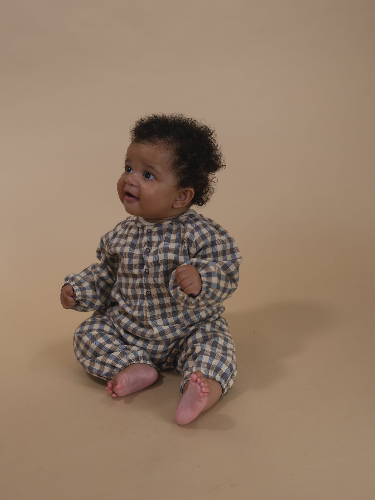 baby wearing cream and blue gingham flannel onesie with gathered cuffs, and front poppers