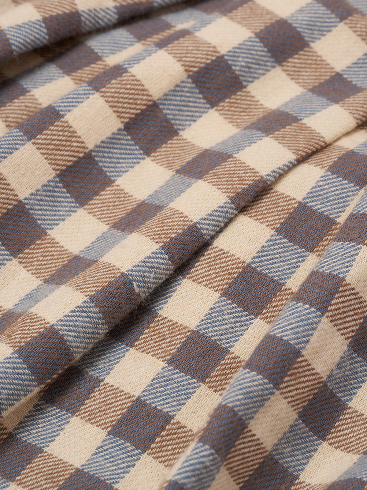 close up of cream and blue gingham flannel pleated pinafore skirt with adjustable straps