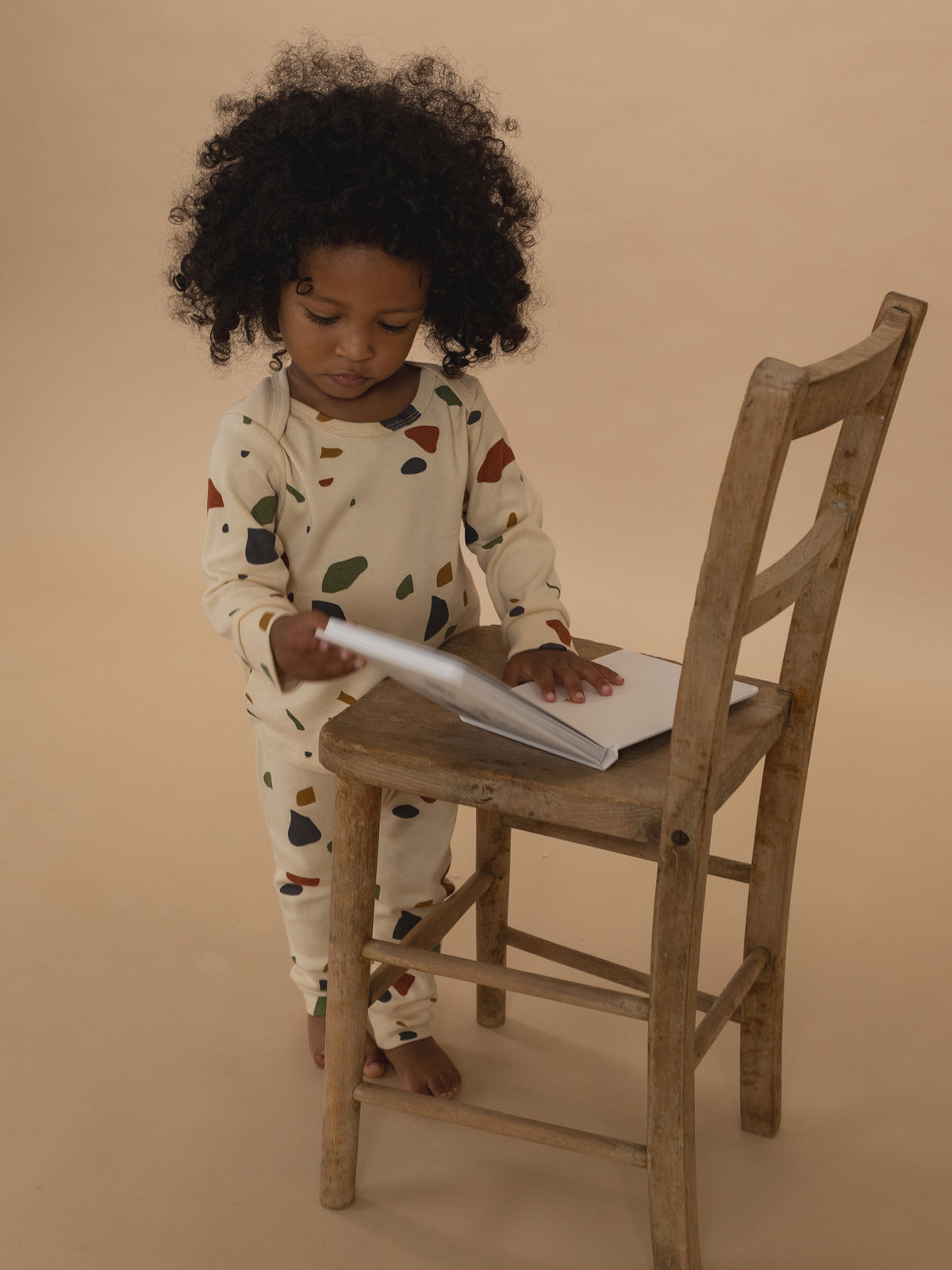 toddler in cream ribbed cotton long-sleeved top & leggings set with terrazzo print, reading book