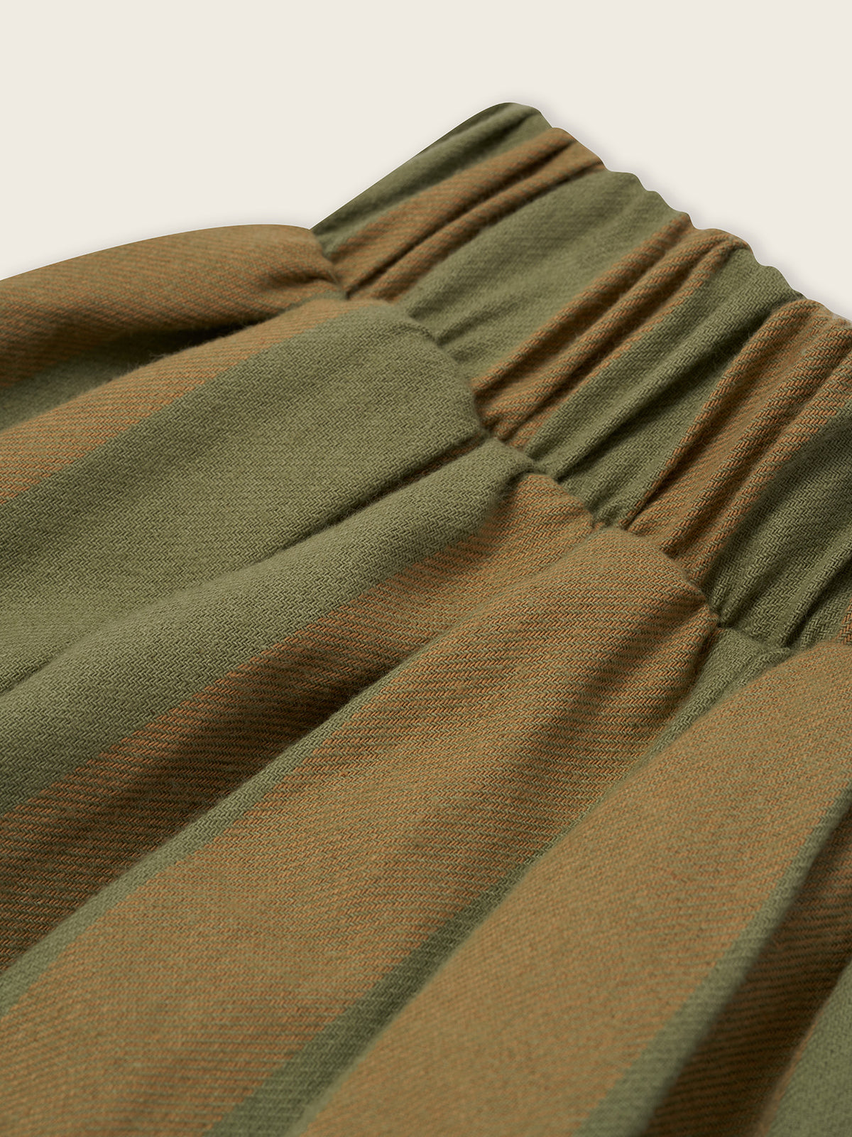 close up of flannel balloon pants in cream and green stripes, with elastic waistband