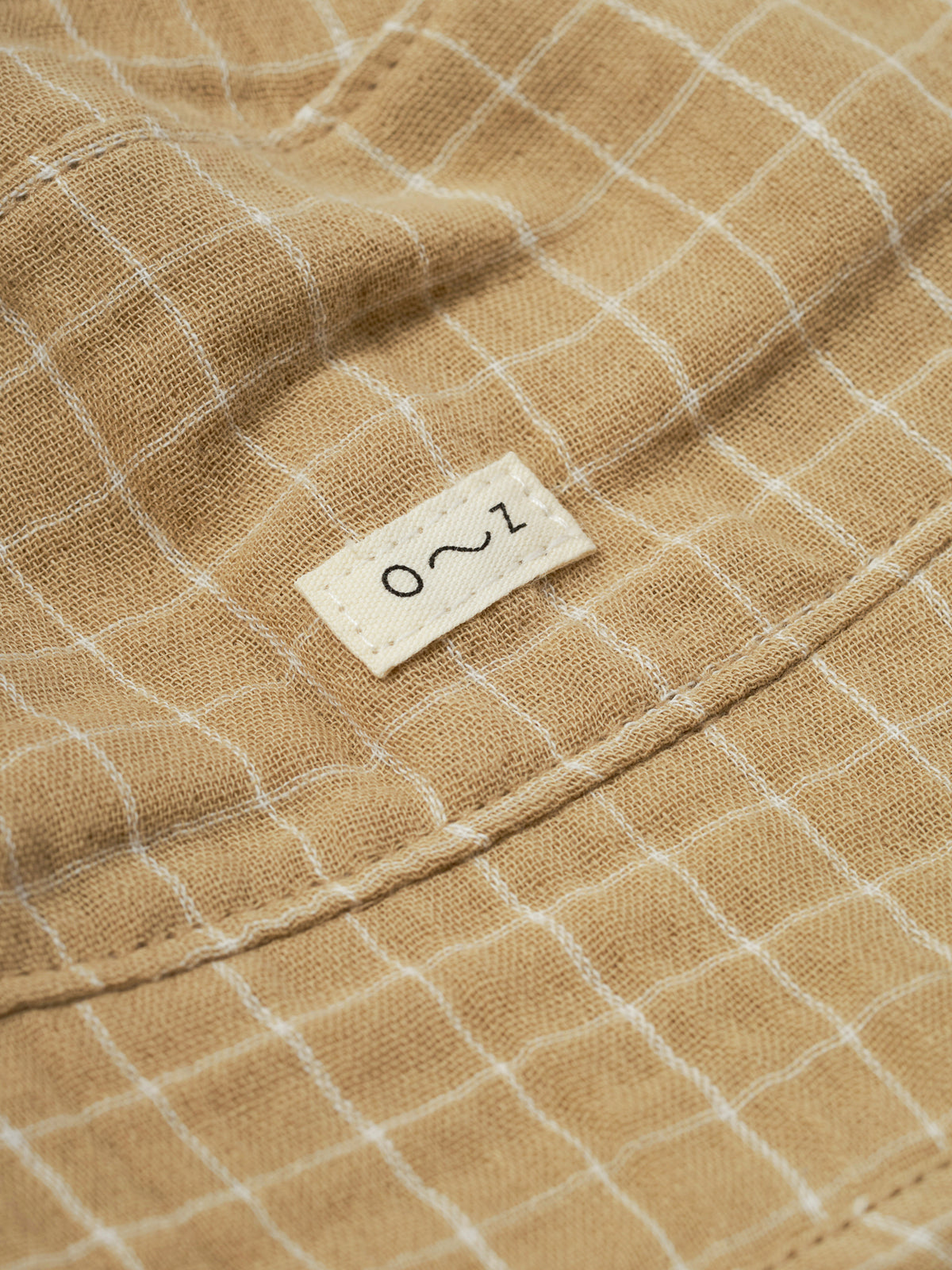 close up of baby and toddler gold grid check organic muslin bucket hat with chin ties