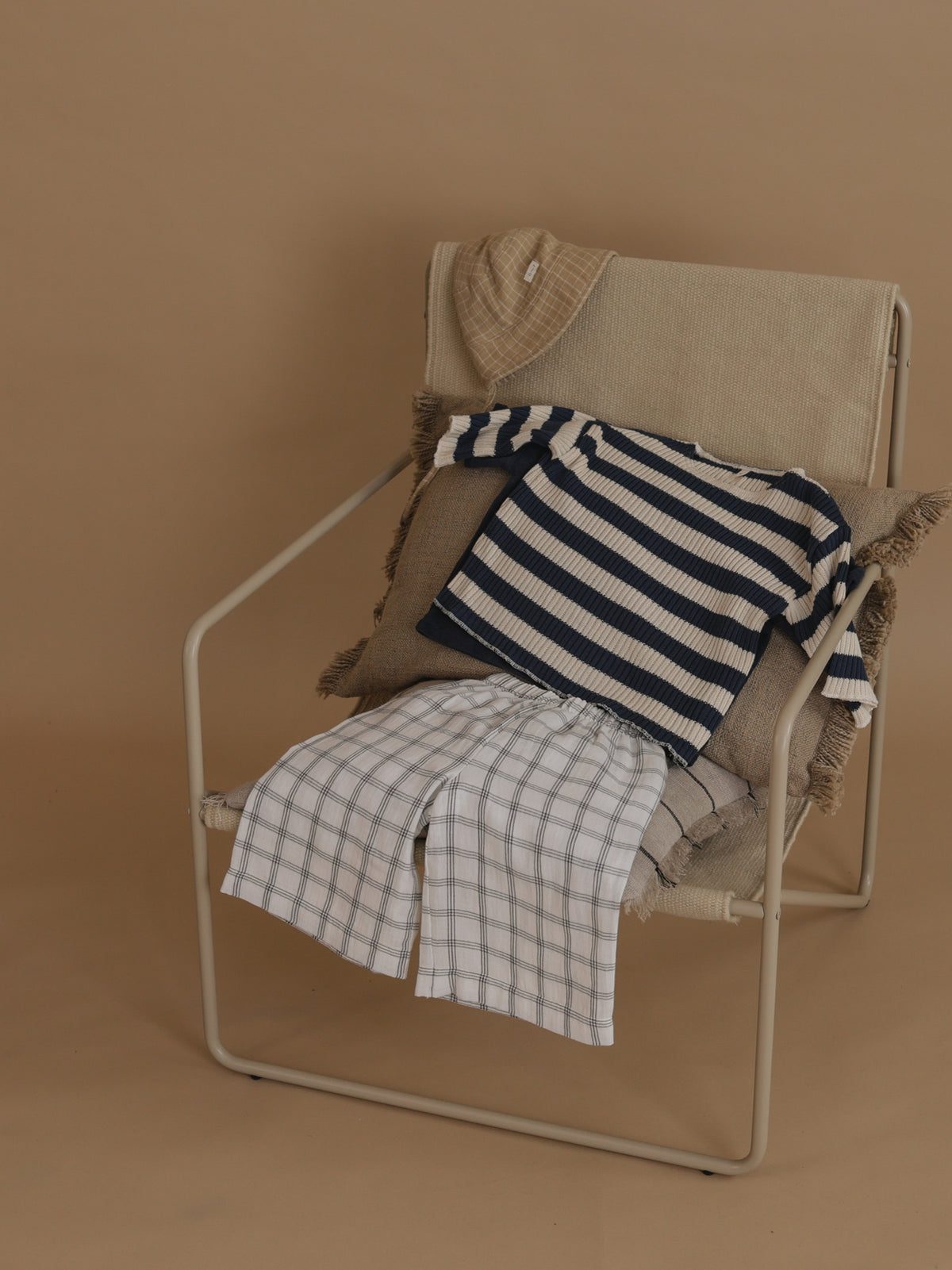 flat lay of white wide leg window check pants, striped sweater & bucket hat on chair