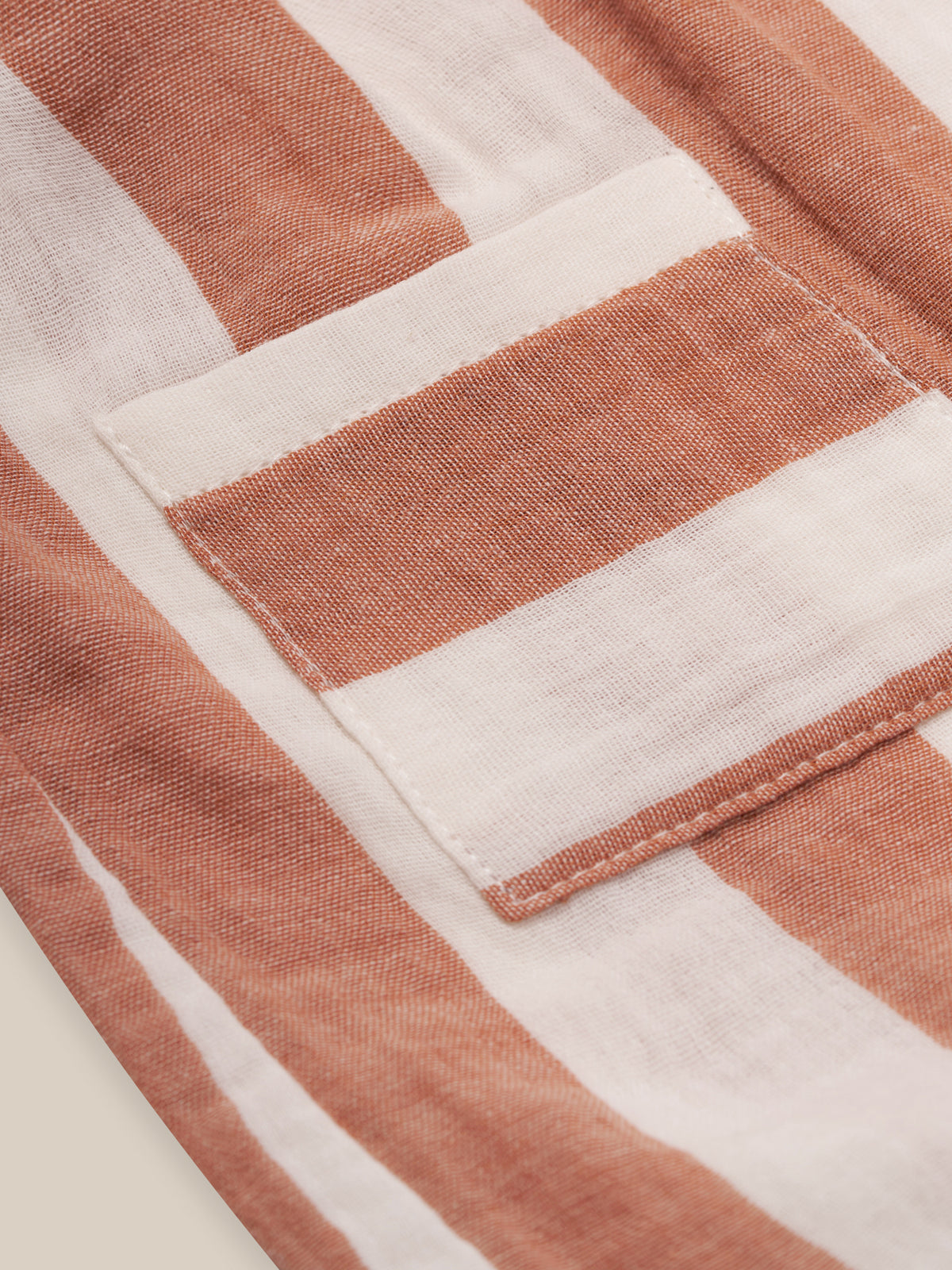 close up of baby & toddler organic muslin red striped artisan jumpsuit with gathered straps & pockets