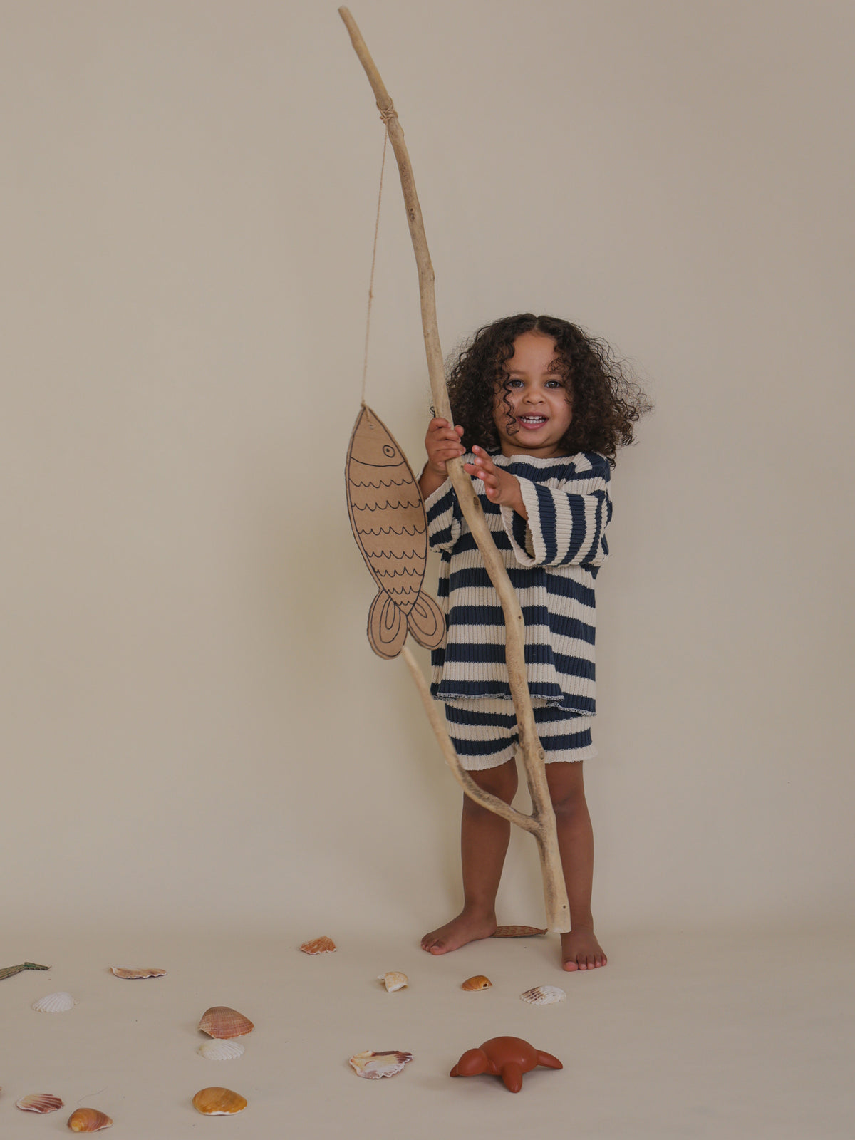 toddler in matching rib knitted navy striped sweater & shorts holding branch