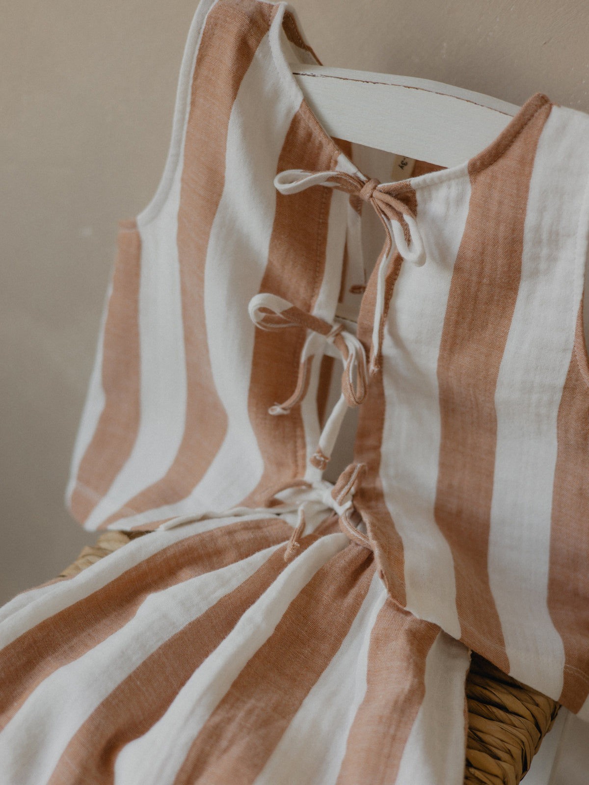toddler ribbon front-tie sleeveless muslin top with fun sienna red stripes draped over chair