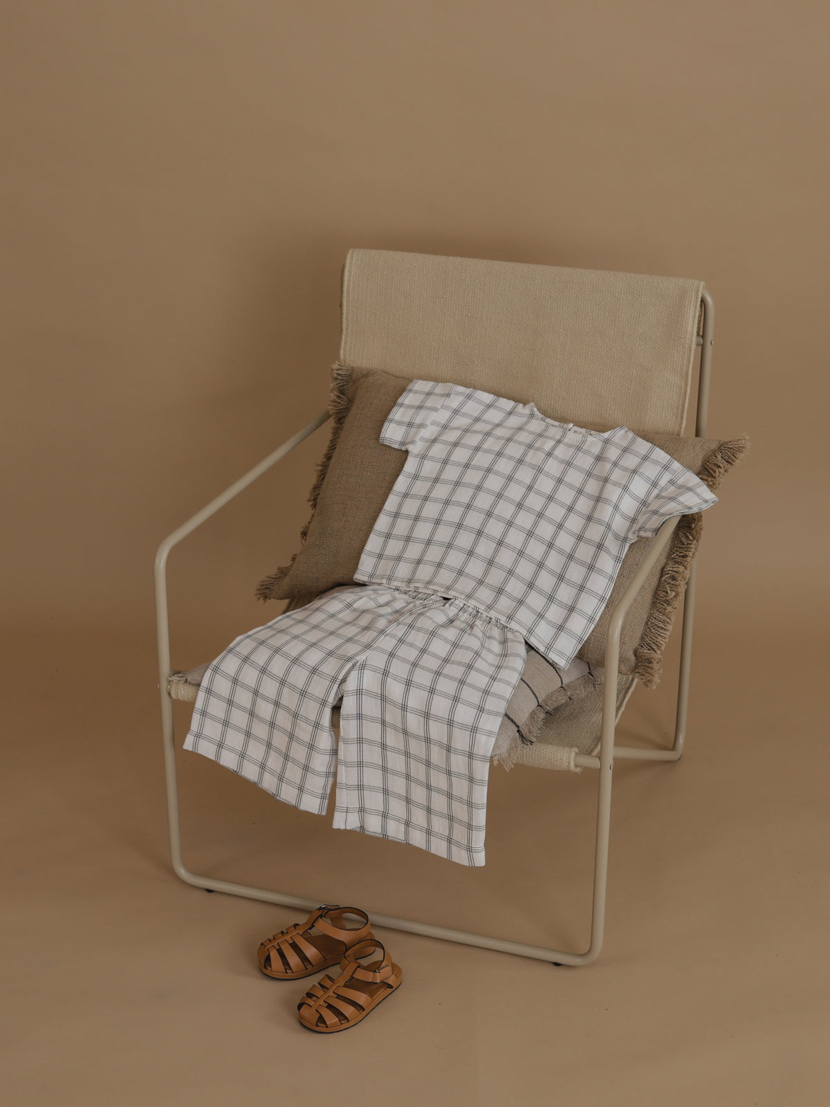 flat lay of matching boxy navy window check t-shirt & pants on chair, with sandals on floor