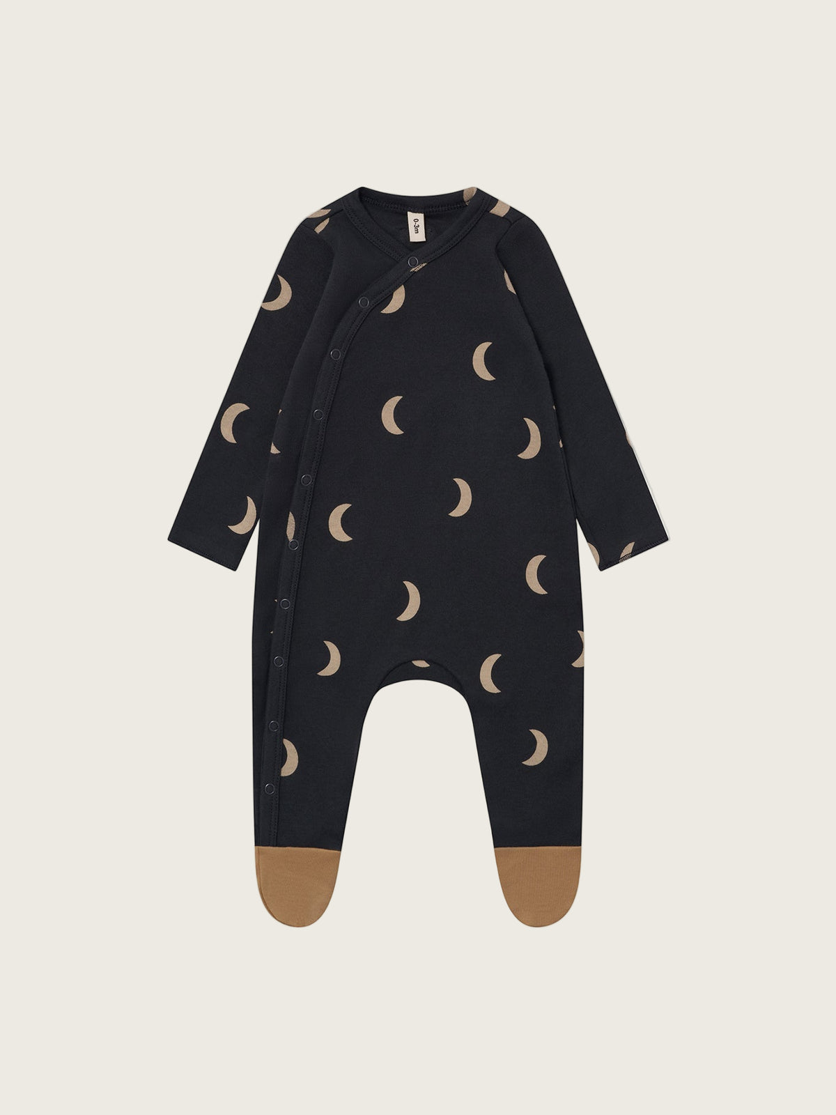 Black baby onesie with moon pattern on a beige background