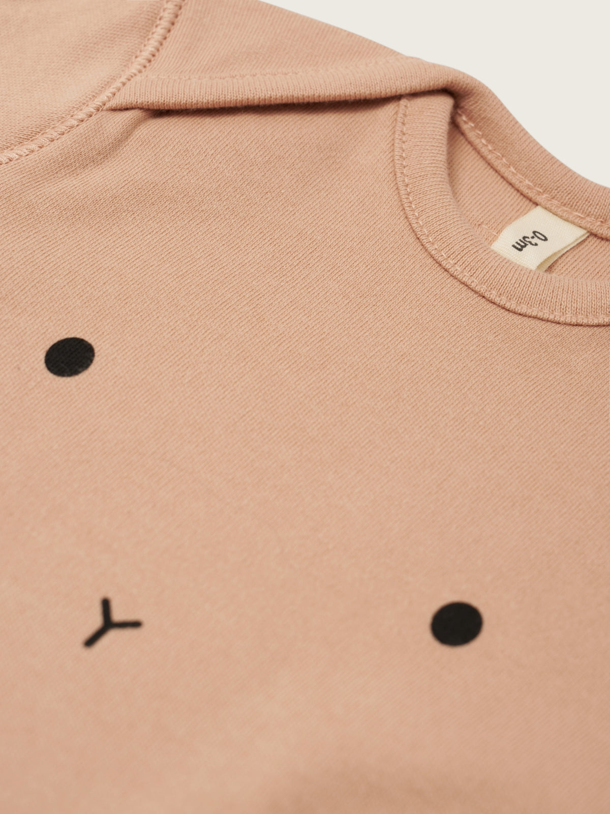 Close-up of a beige garment with black dot patterns on a beige background