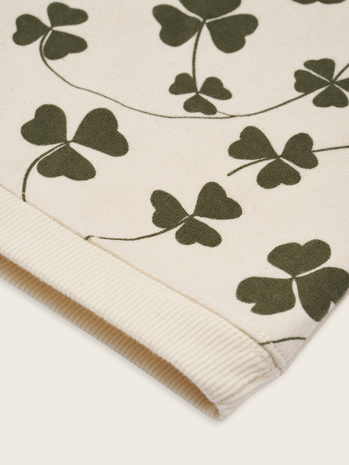 close up of baby and toddler cream undyed cotton sweatshirt with green clover print