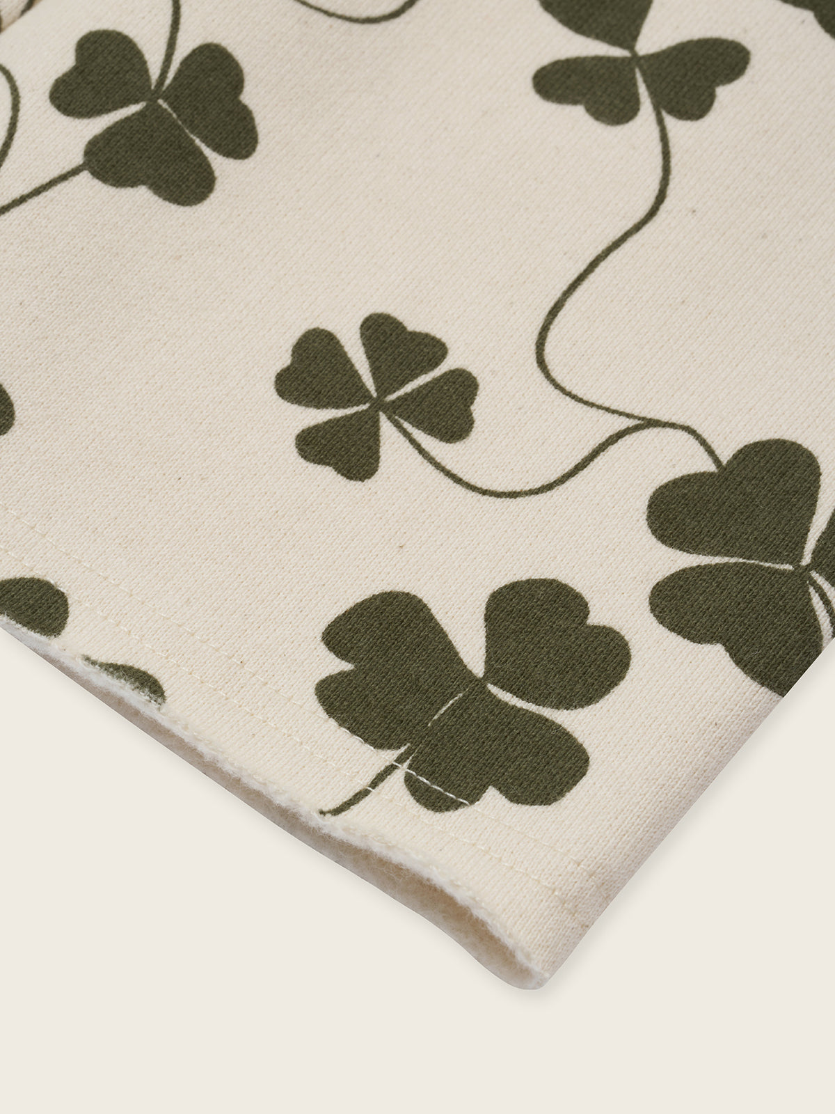 close up of cream undyed cotton wide leg drawstring pants with green clover print