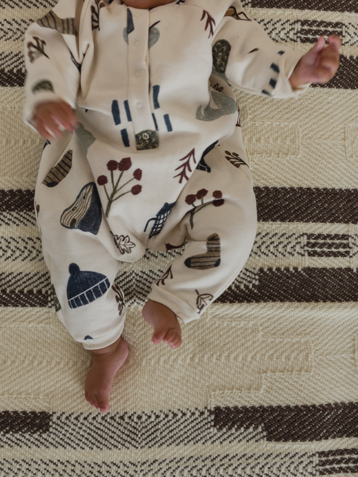 close up of a baby in cream undyed cotton onesie with cosy nature-themed hand-drawn prints