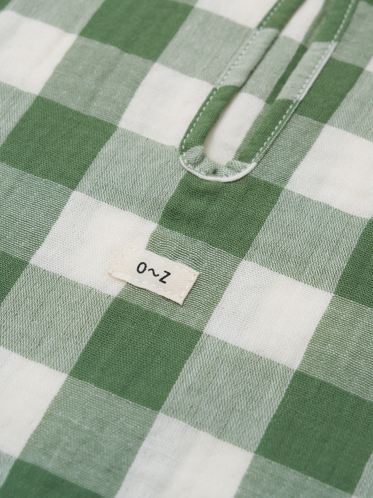 Close-up of a green and white checkered t-shirt with a label on a green background