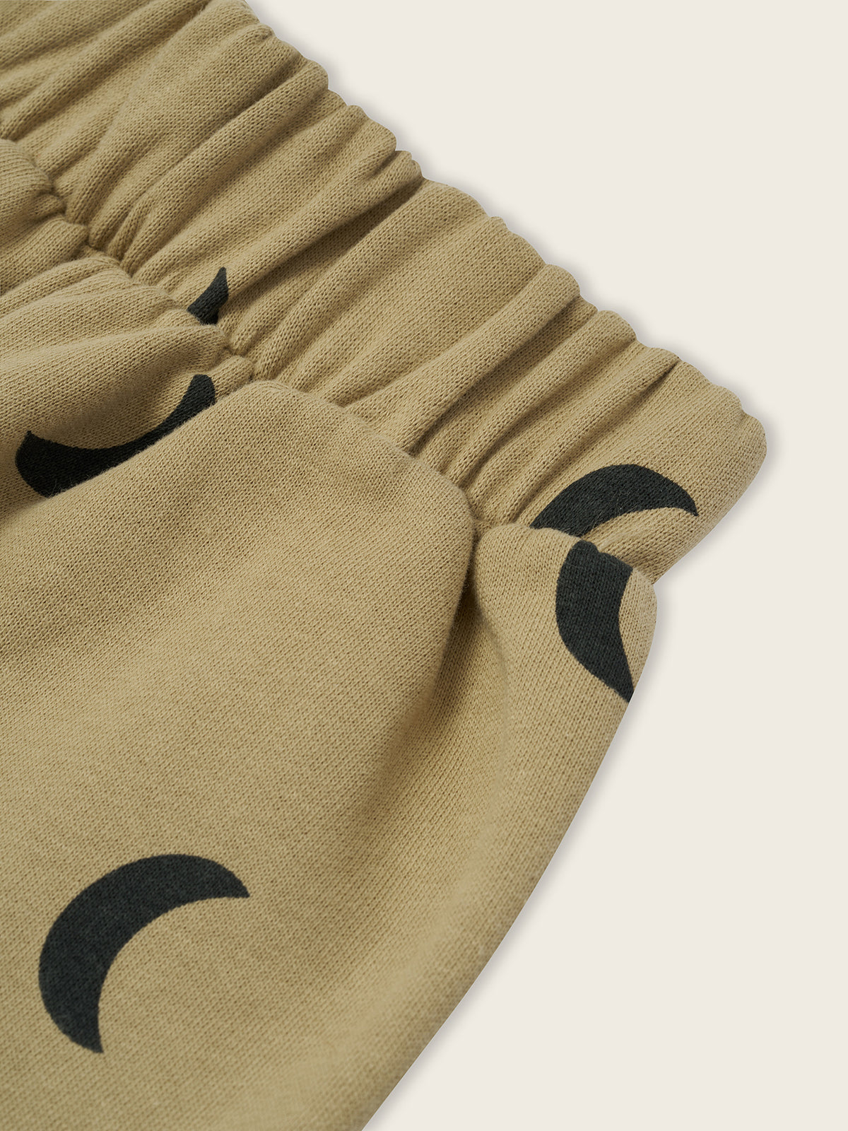 close up of dusky beige trousers with black crescent moon print and elastic waistband
