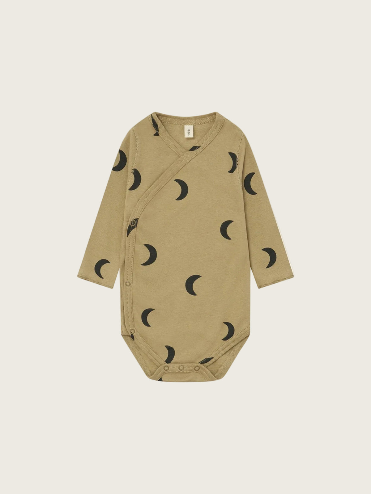 A long-sleeve baby bodysuit in a warm tan/khaki color, featuring an all-over black crescent moon pattern, displayed flat against a solid white background.