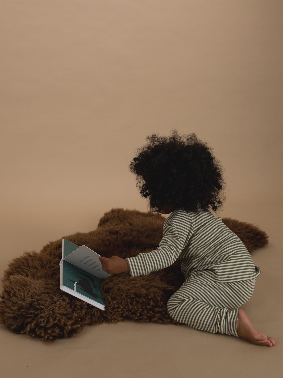 toddler in ribbed cotton long-sleeved top & leggings set in green & cream stripes, reading book