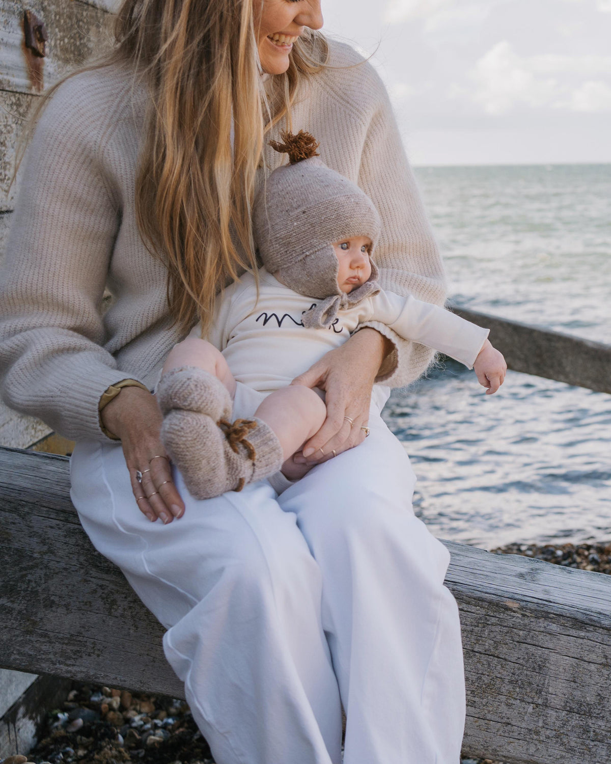 Mom holding a baby in undyed cotton bodysuit by the water