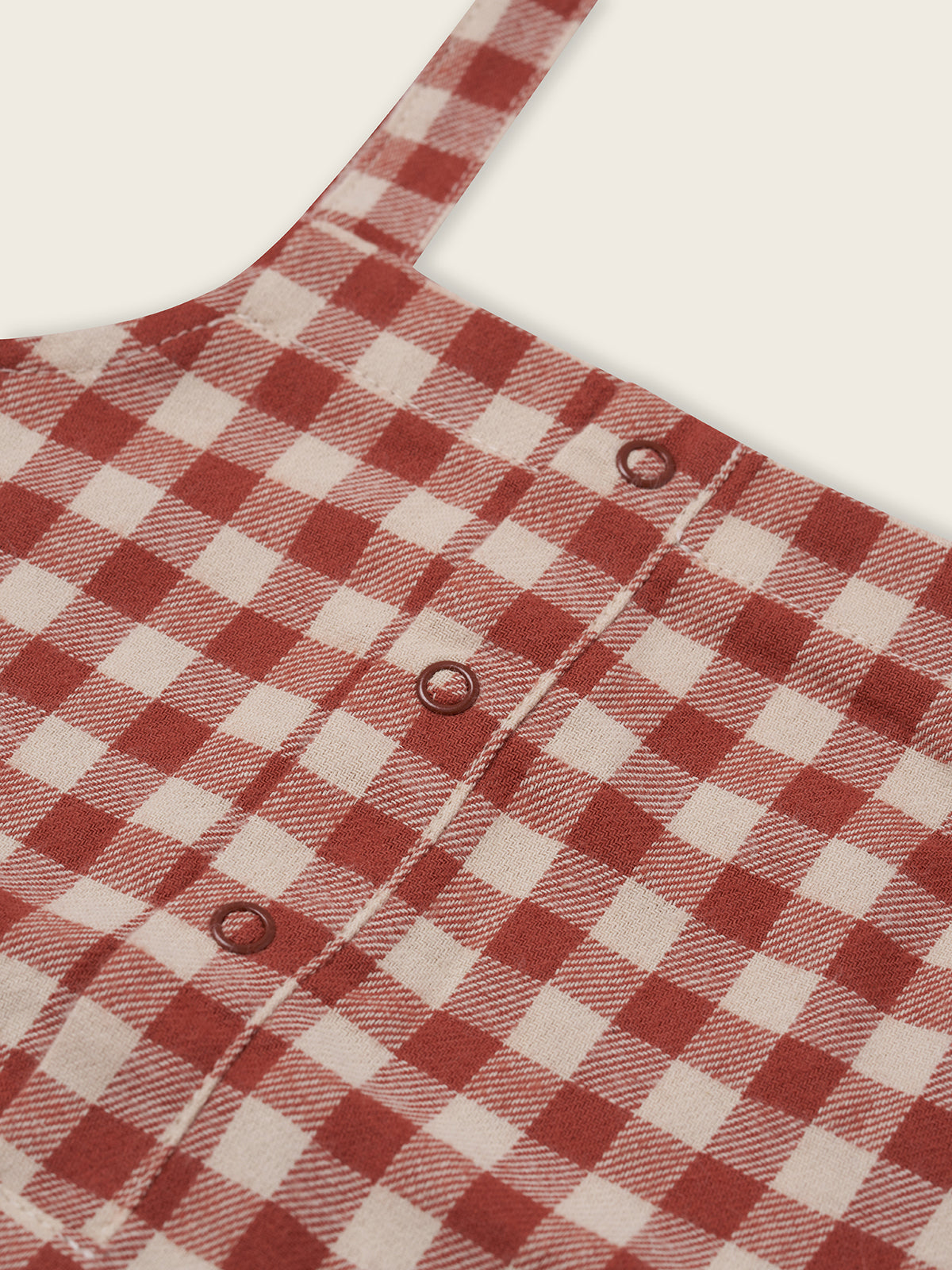 close up of paprika red and cream gingham flannel salopette with front poppers