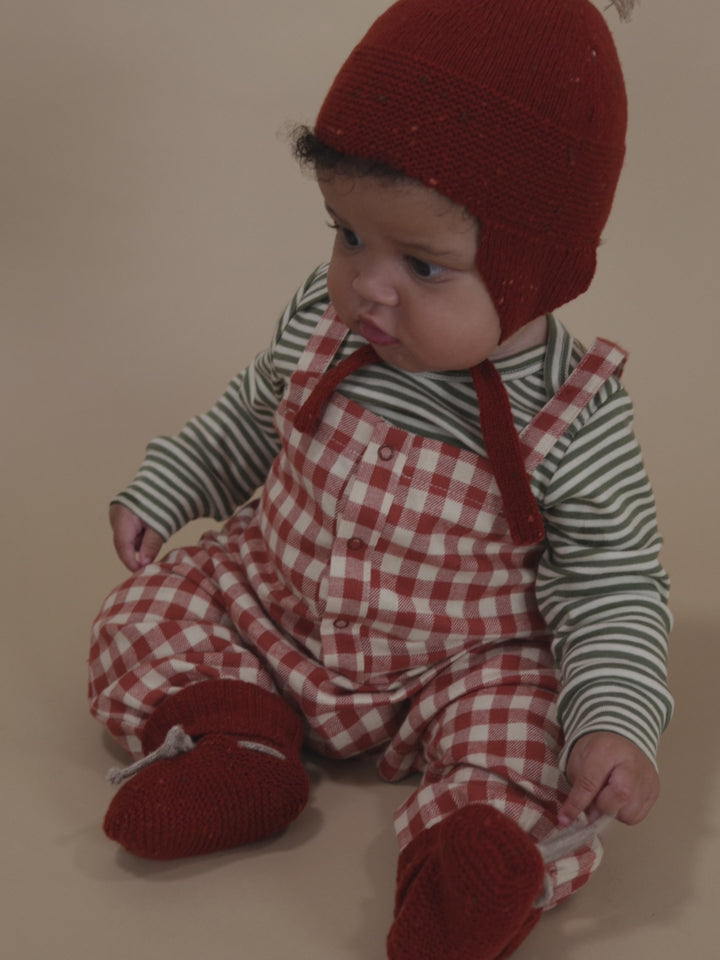 baby in paprika red and cream gingham flannel salopette with green striped sweatshirt and tassel hat