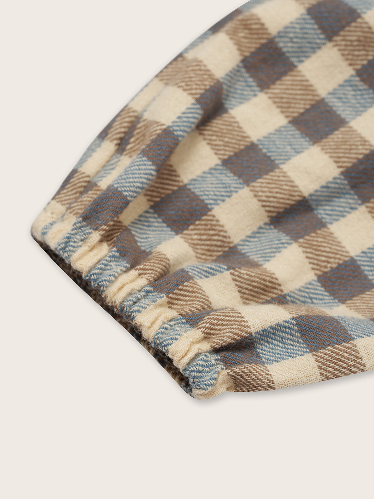 close up of baby and toddler checkered cream and blue gingham flannel onesie with gathered cuffs